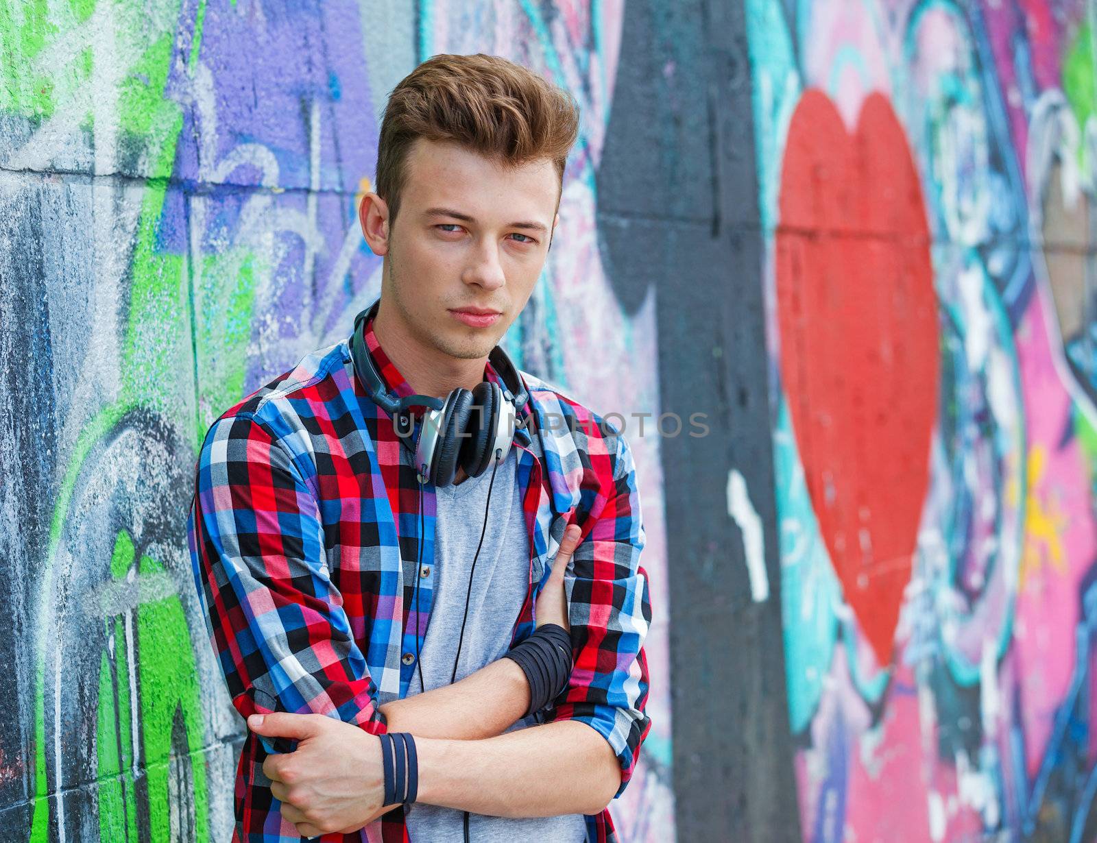 Portrait of happy teens boy with headphones near painted wall