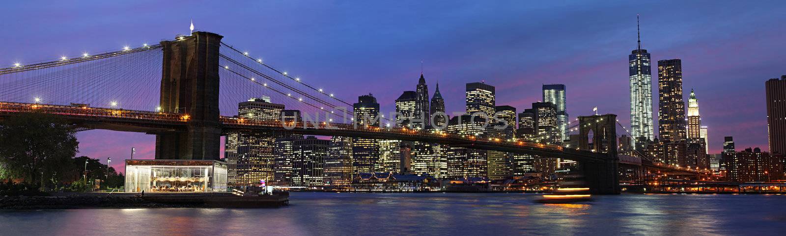 Panorama of Brooklyn Bridge, East River and Manhattan at sunset with lights and reflections. New York