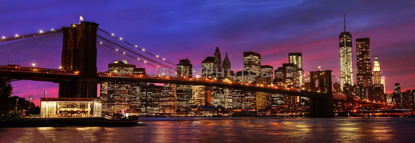 Panorama of Brooklyn Bridge, East River and Manhattan at sunset with lights and reflections. New York