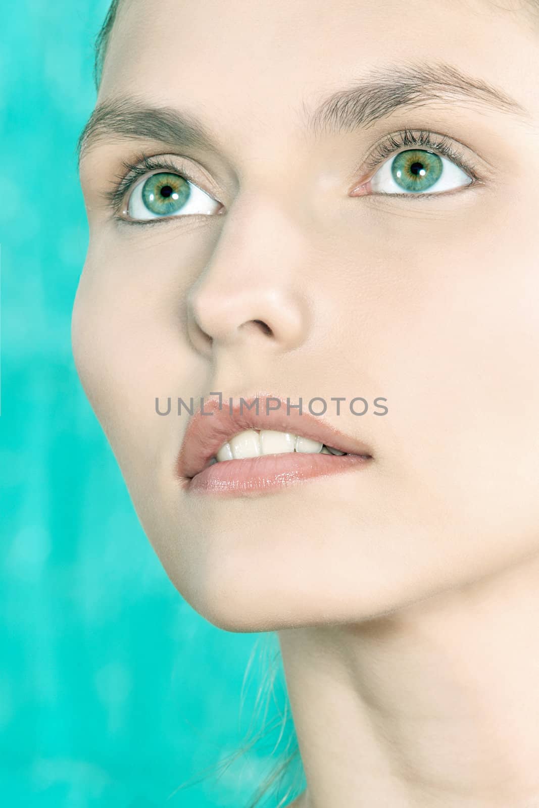 studio shot beauty portrait of a beautiful green eyes caucasian young woman on a blue background