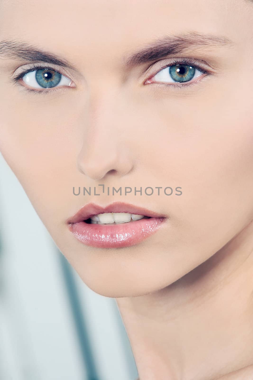 studio shot beauty portrait of a beautiful green eyes caucasian young woman on a blue background