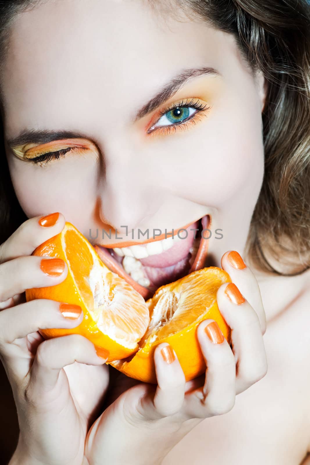 studio portrait of a beautiful woman holding orange mandarine citrus fruit