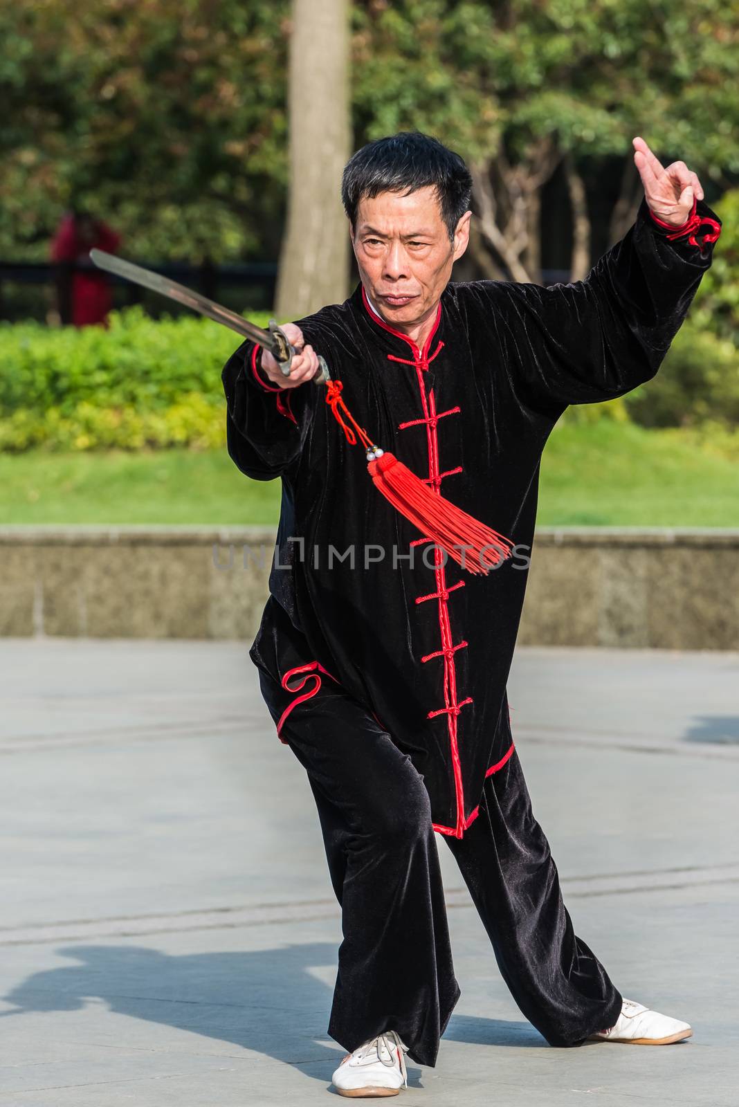 Shanghai, China - April 7, 2013: one man exercising tai chi with traditional costume in gucheng park in the city of Shanghai in China on april 7th, 2013