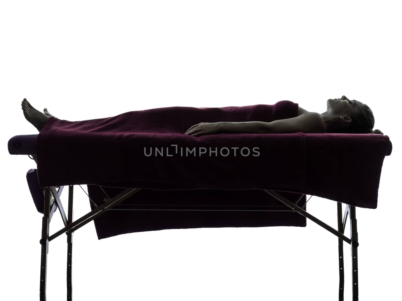 one woman lying on a massage table in silhouette studio on white background