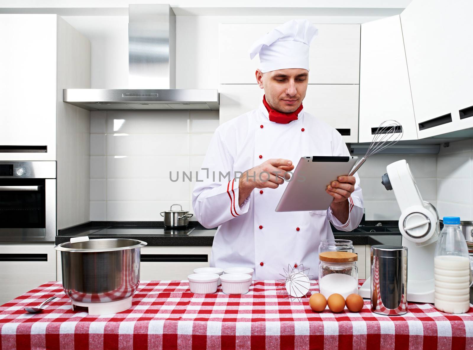 Male chef at kitchen with tablet pc getting ready to cook