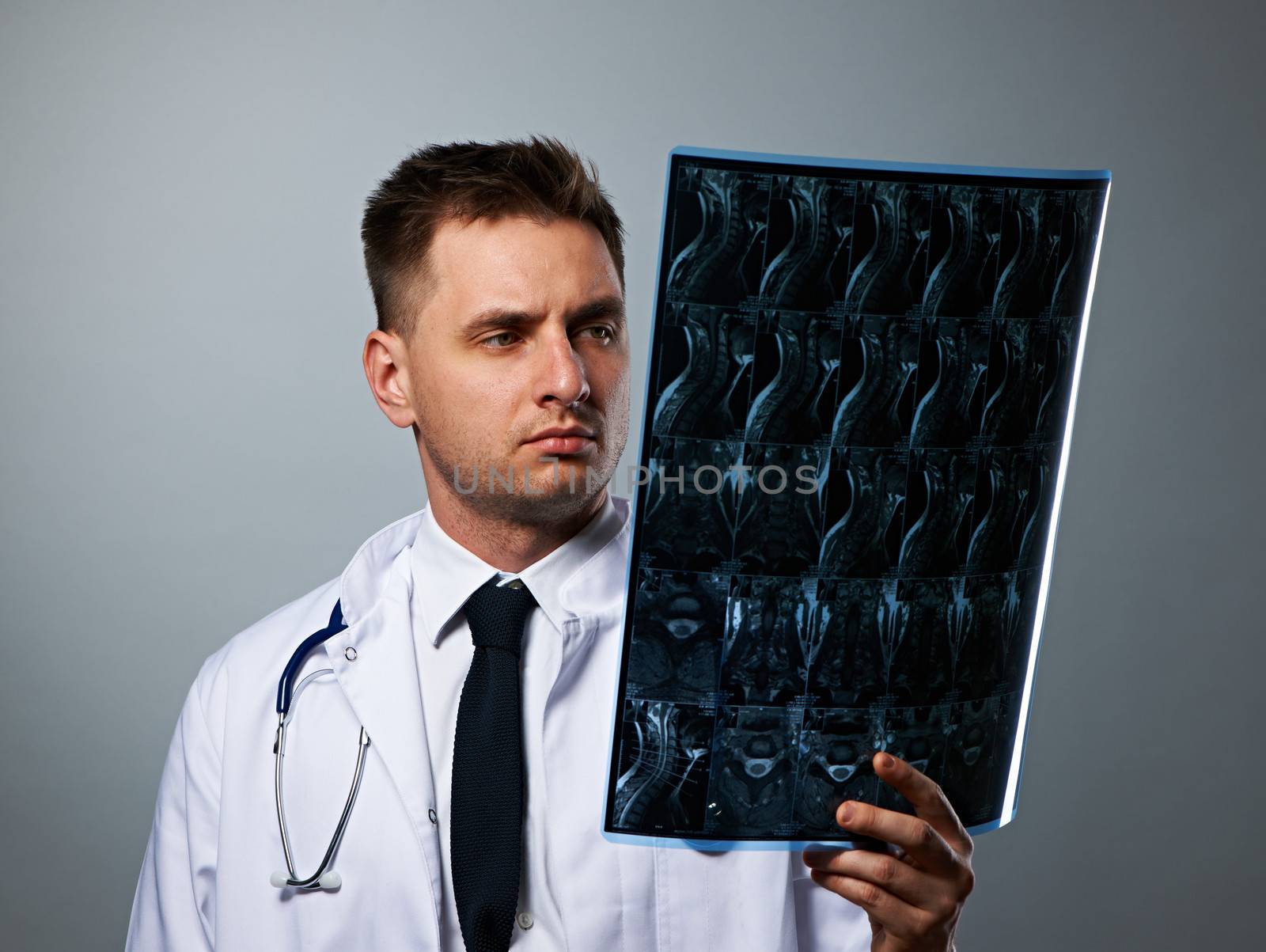 Medical doctor with MRI spinal scan portrait against grey background 