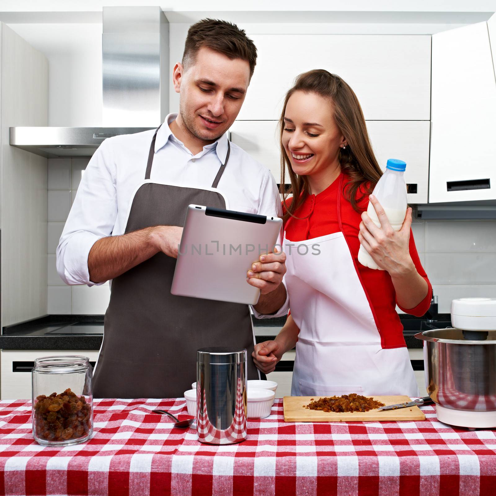 Couple at kitchen cooking together with tablet pc