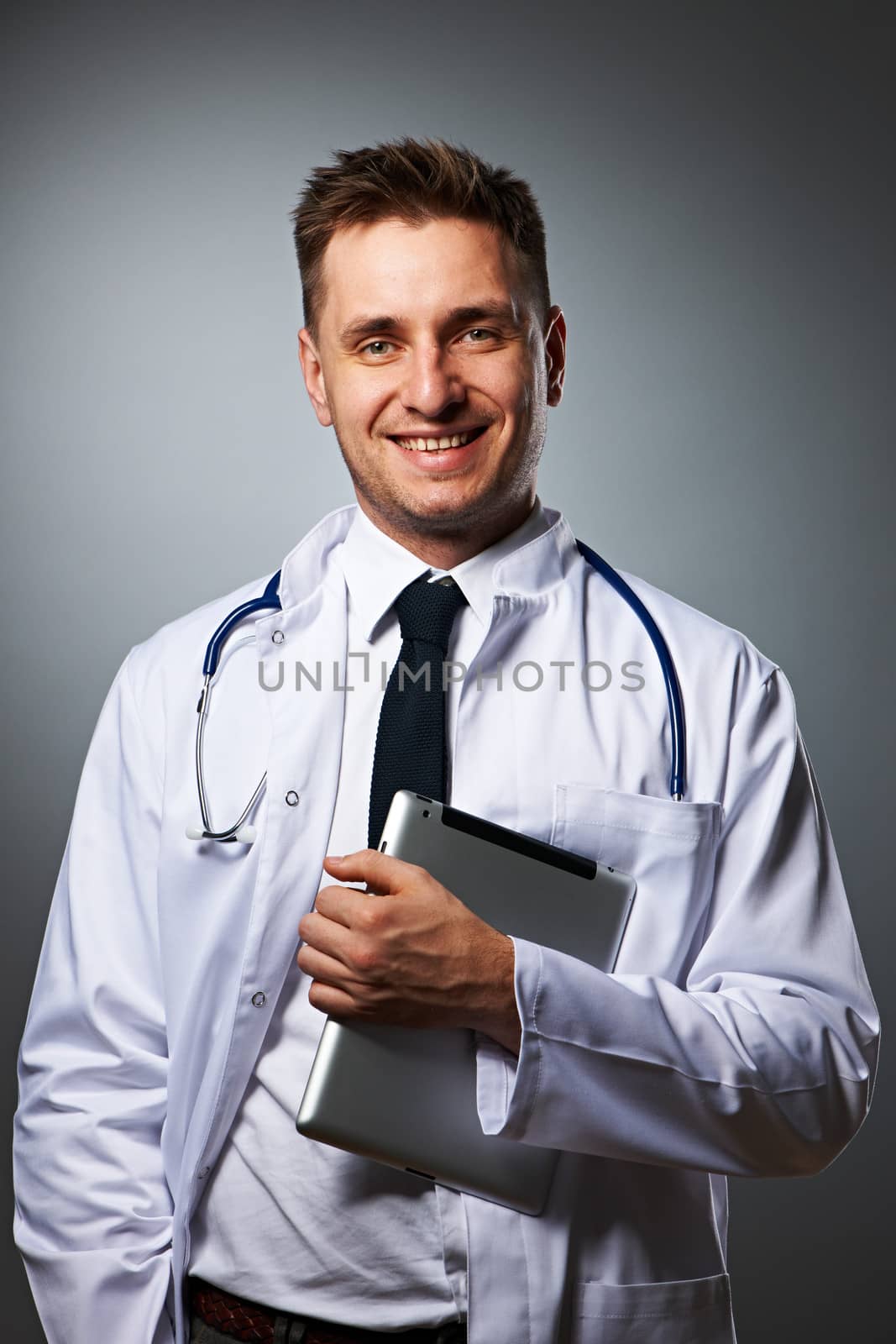 Medical doctor with tablet pc portrait against grey background 