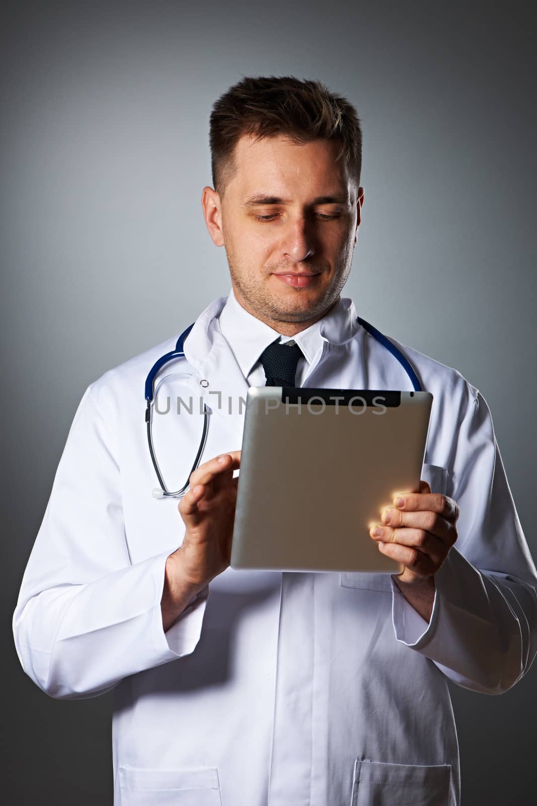 Medical doctor with tablet pc portrait against grey background 