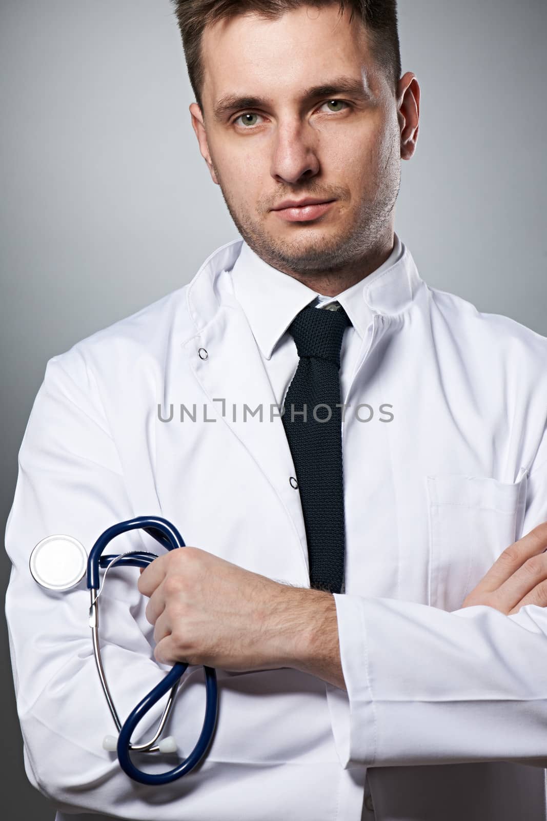 Medical doctor with stethoscope portrait against grey background 