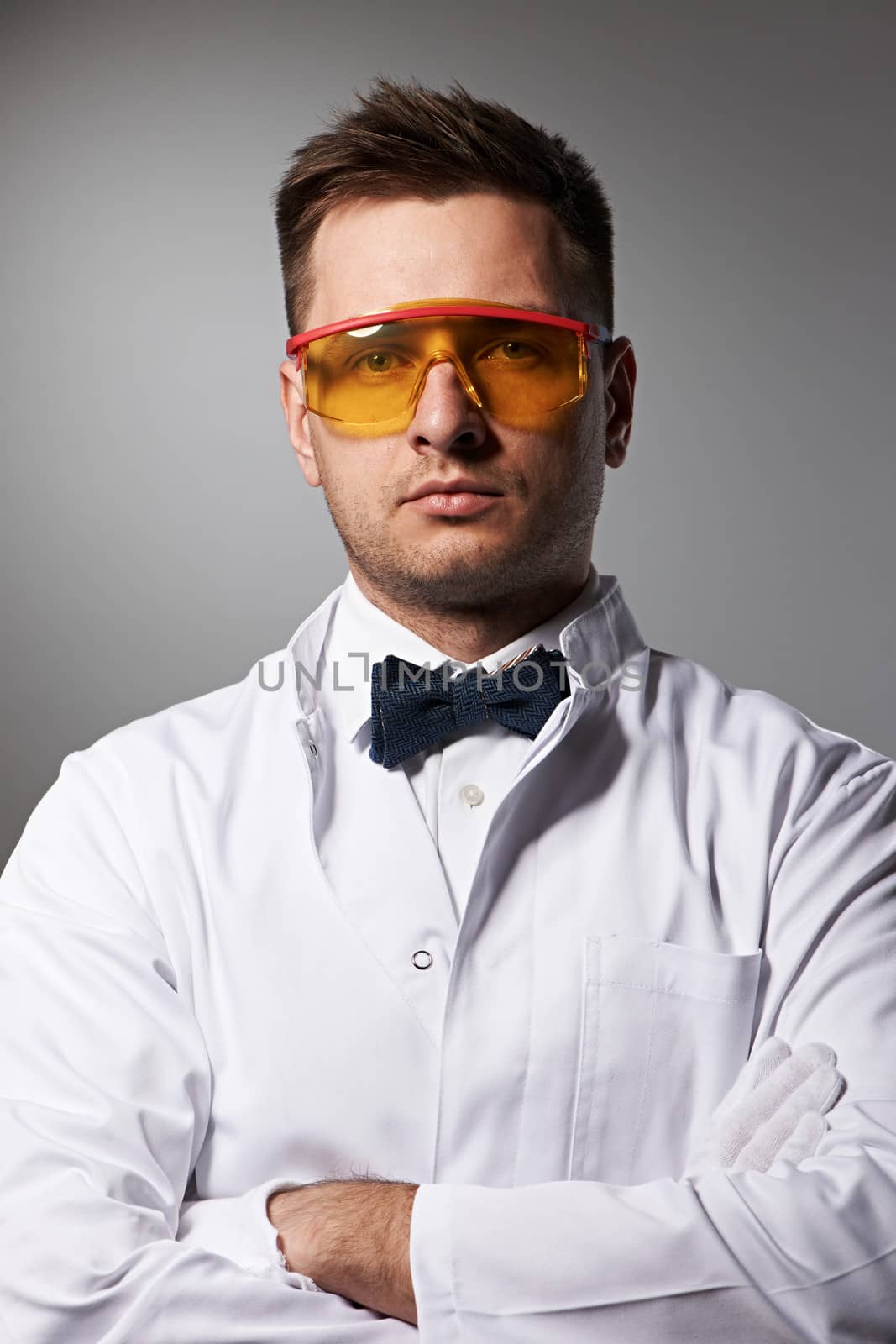 Scientist in yellow glasses against grey background