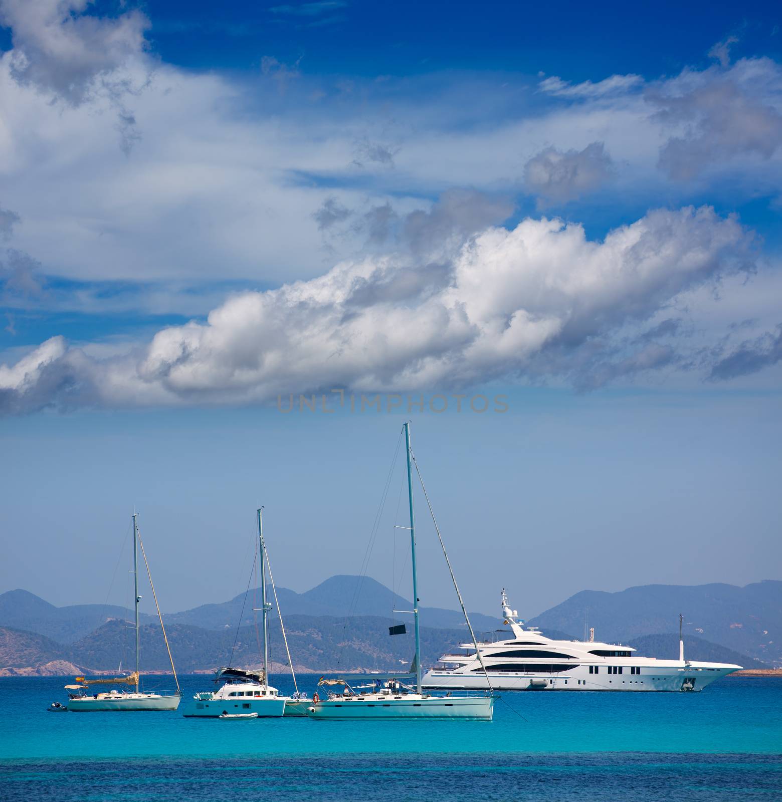 Ibiza coast view from Formentera with anchor boats in blue summer day