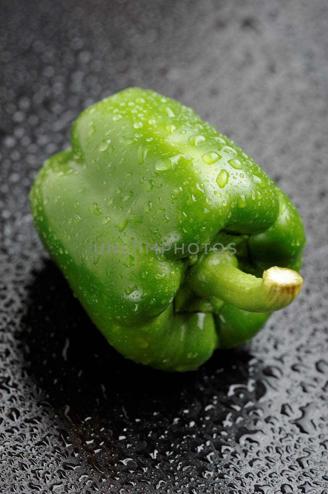 Green bell pepper on black table after rain