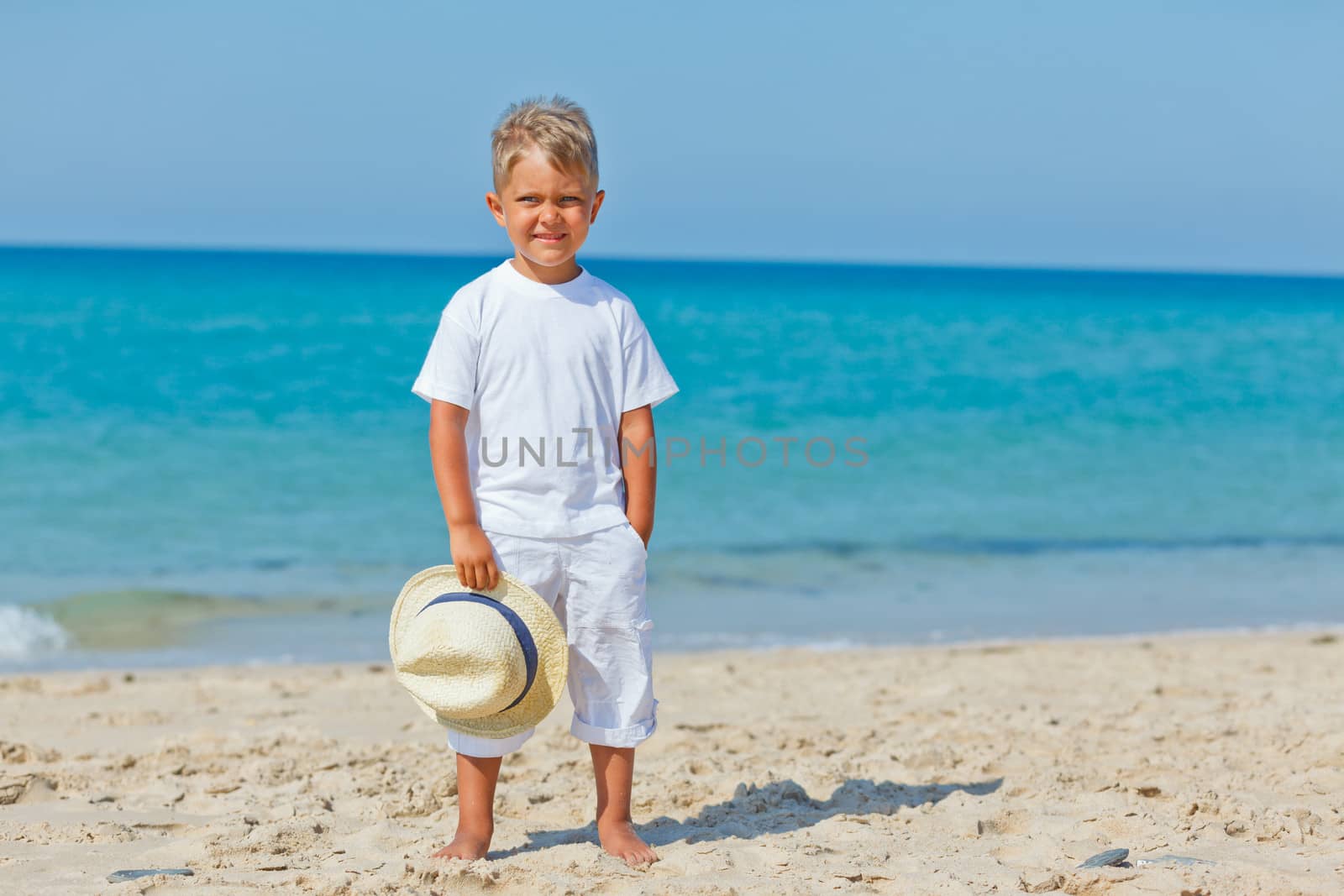 Smiling cute boy with a sun hat at the tropical beach.