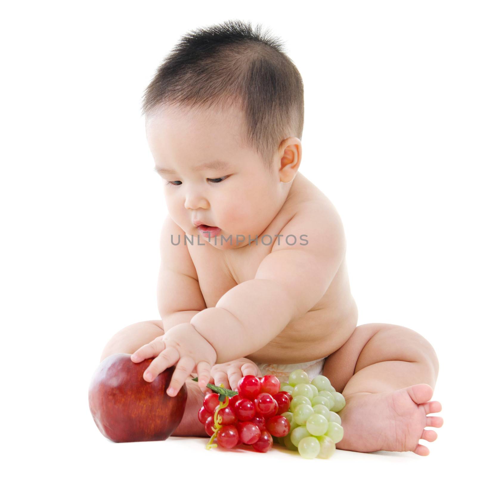 Full body Asian Vegetarian baby playing with fruits sitting isolated on white background