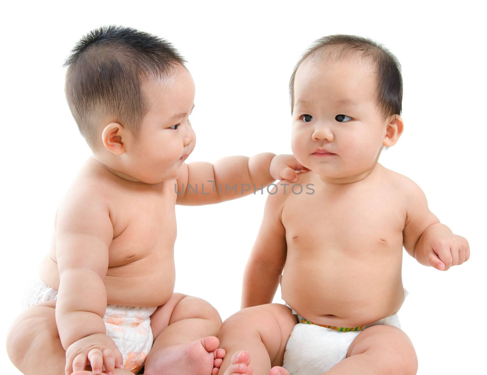 Two Asian babies having baby talk, sitting isolated over white background.