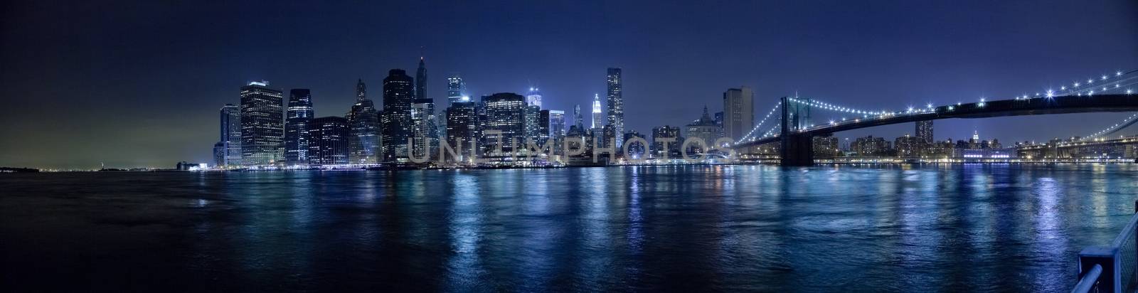 The New York City skyline in the night w Brooklyn Bridge Hi-Res