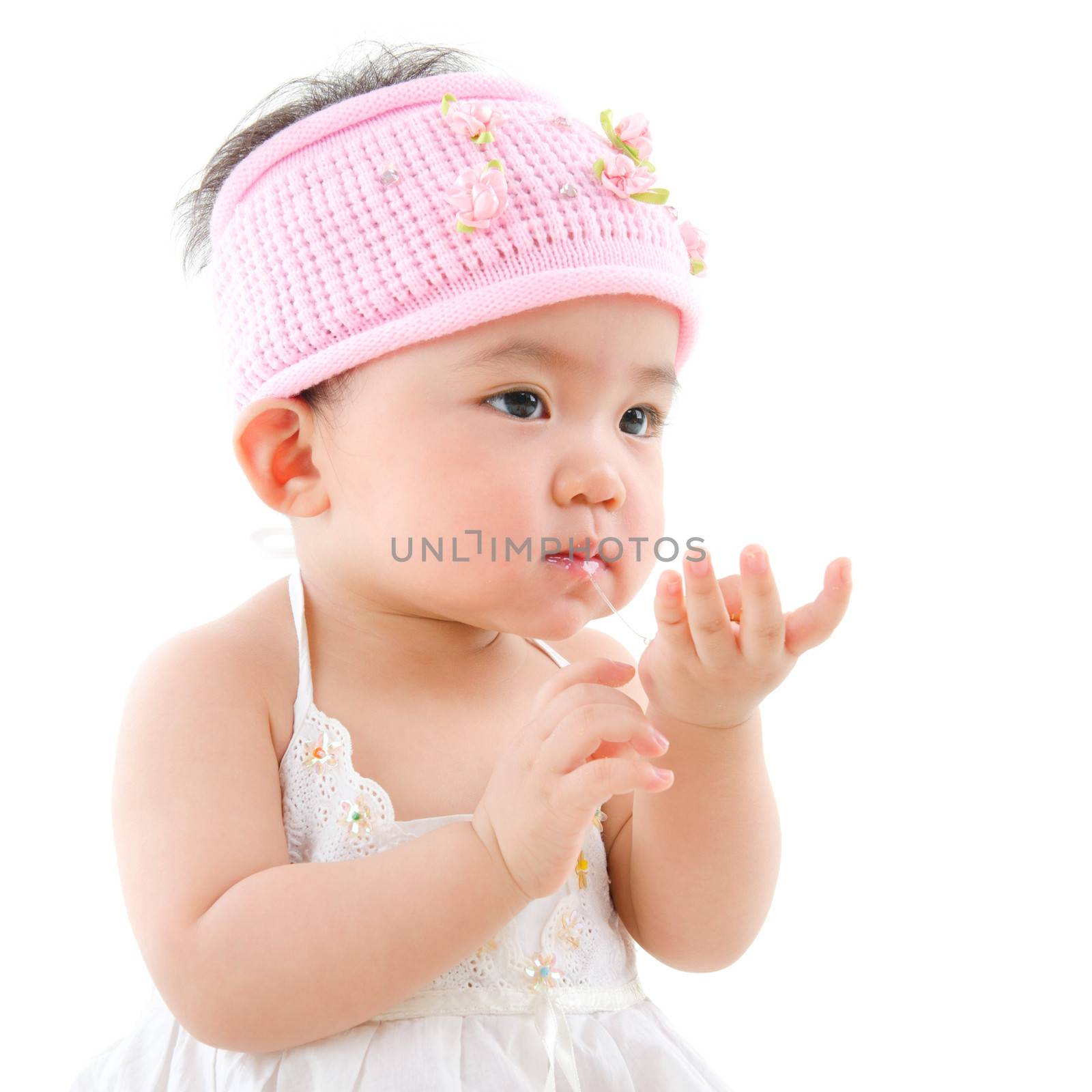 Portrait of cute Asian baby girl  eating,  isolated on white background
