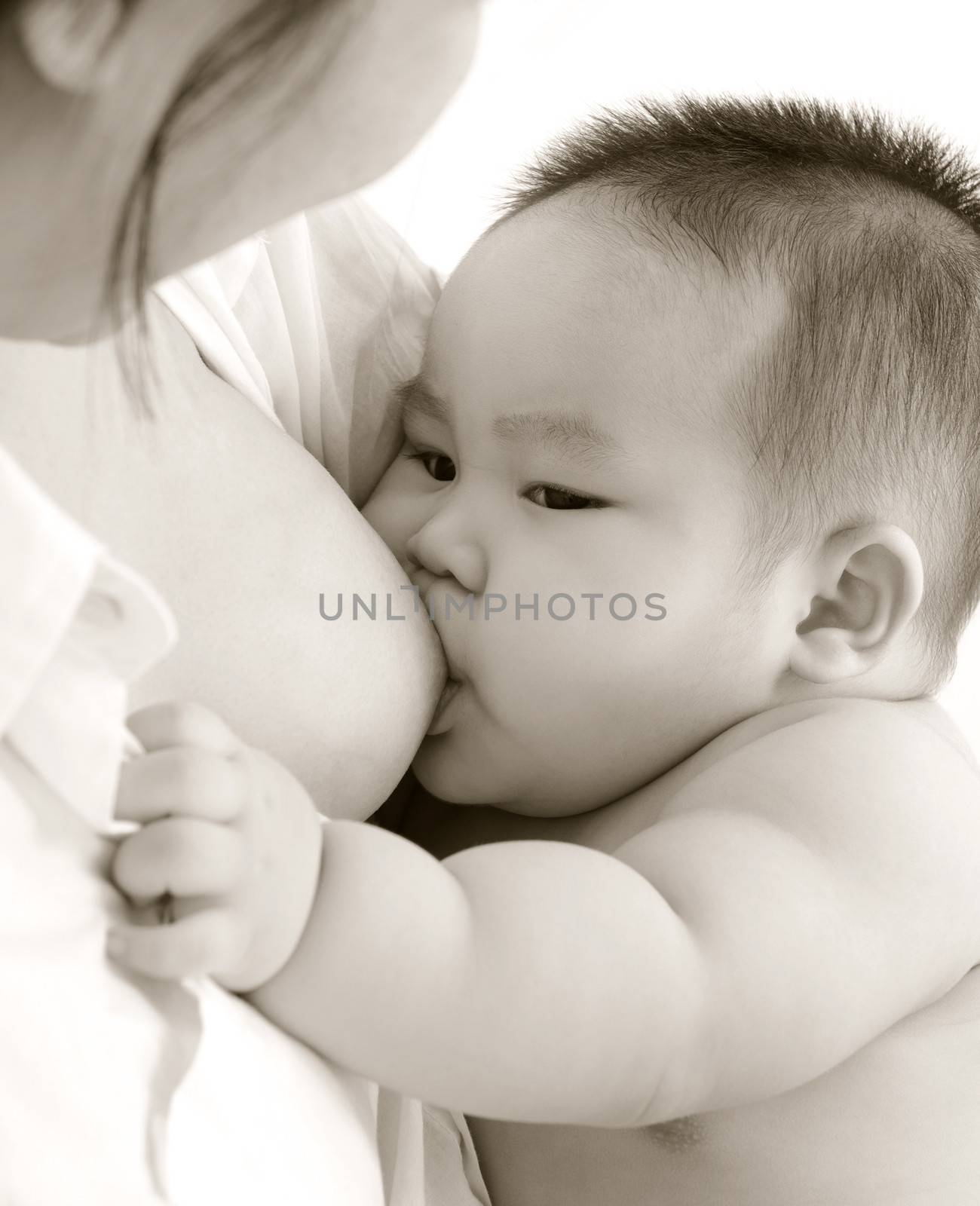 Mother and baby. Close up Asian mother breastfeeding baby boy in sepia tone.