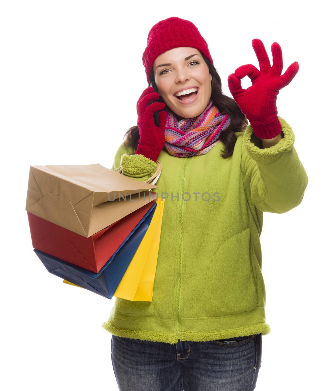 Mixed Race Woman Holding Shopping Bags Talking On Her Cell Phone Giving Ok Gesture Isolated on White Background.
