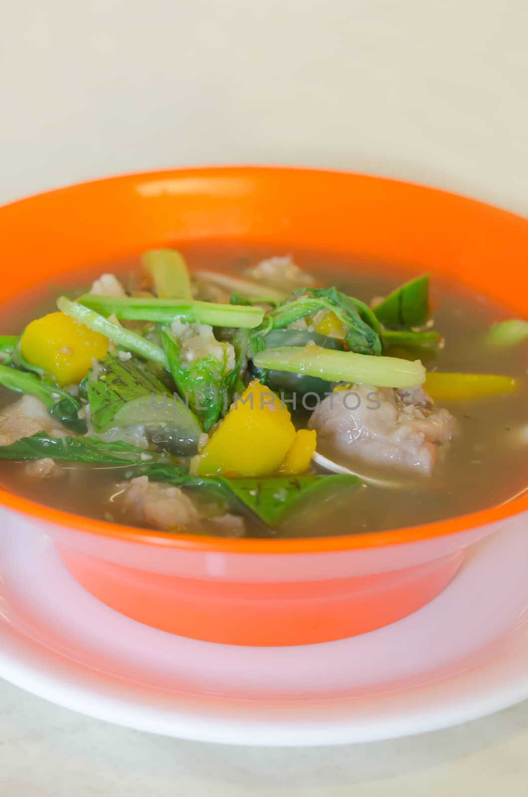 savoury thick soup made from pork , spices and mix vegetable in orange  bowl , asian soup