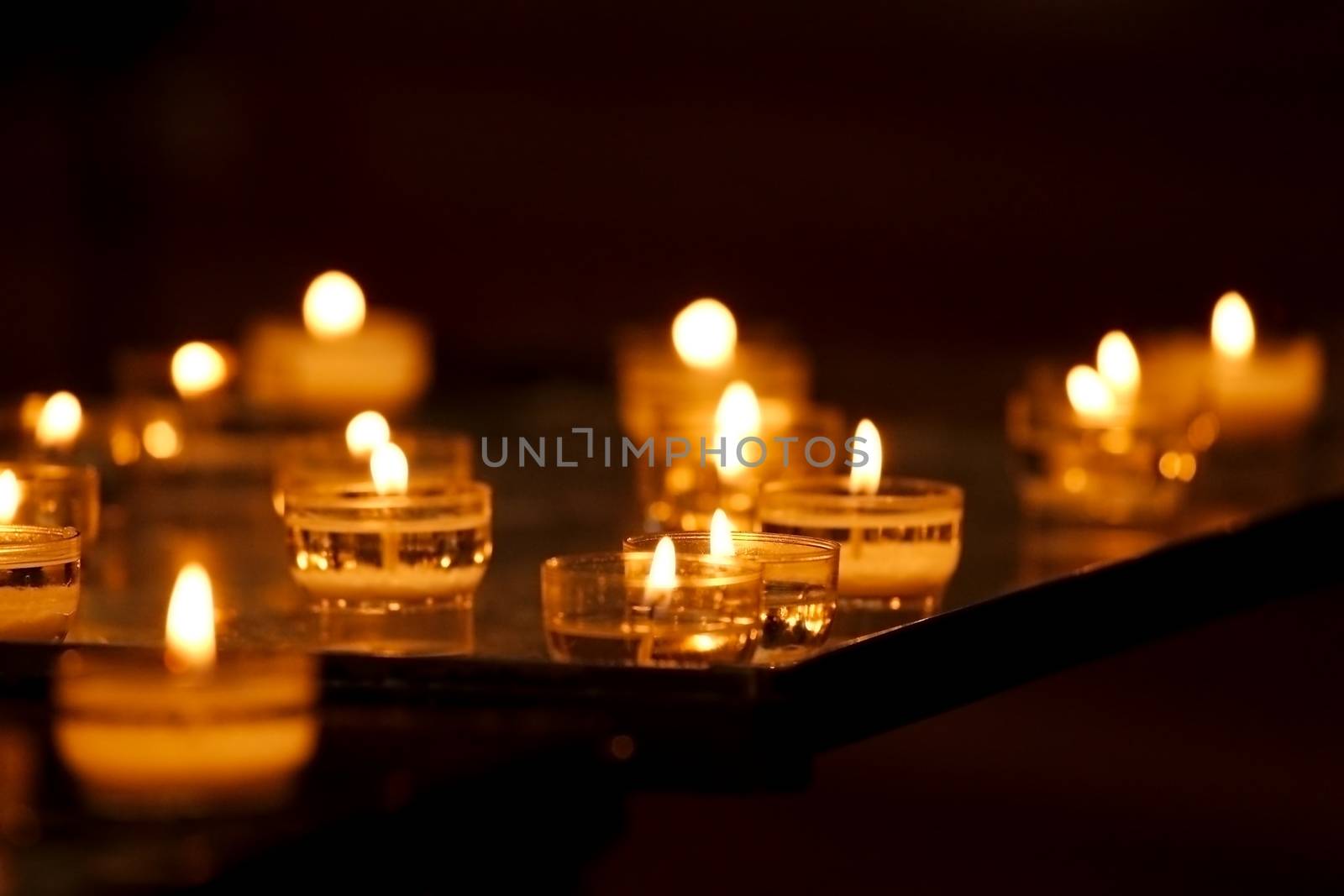 Rows of burning candles in a dim church