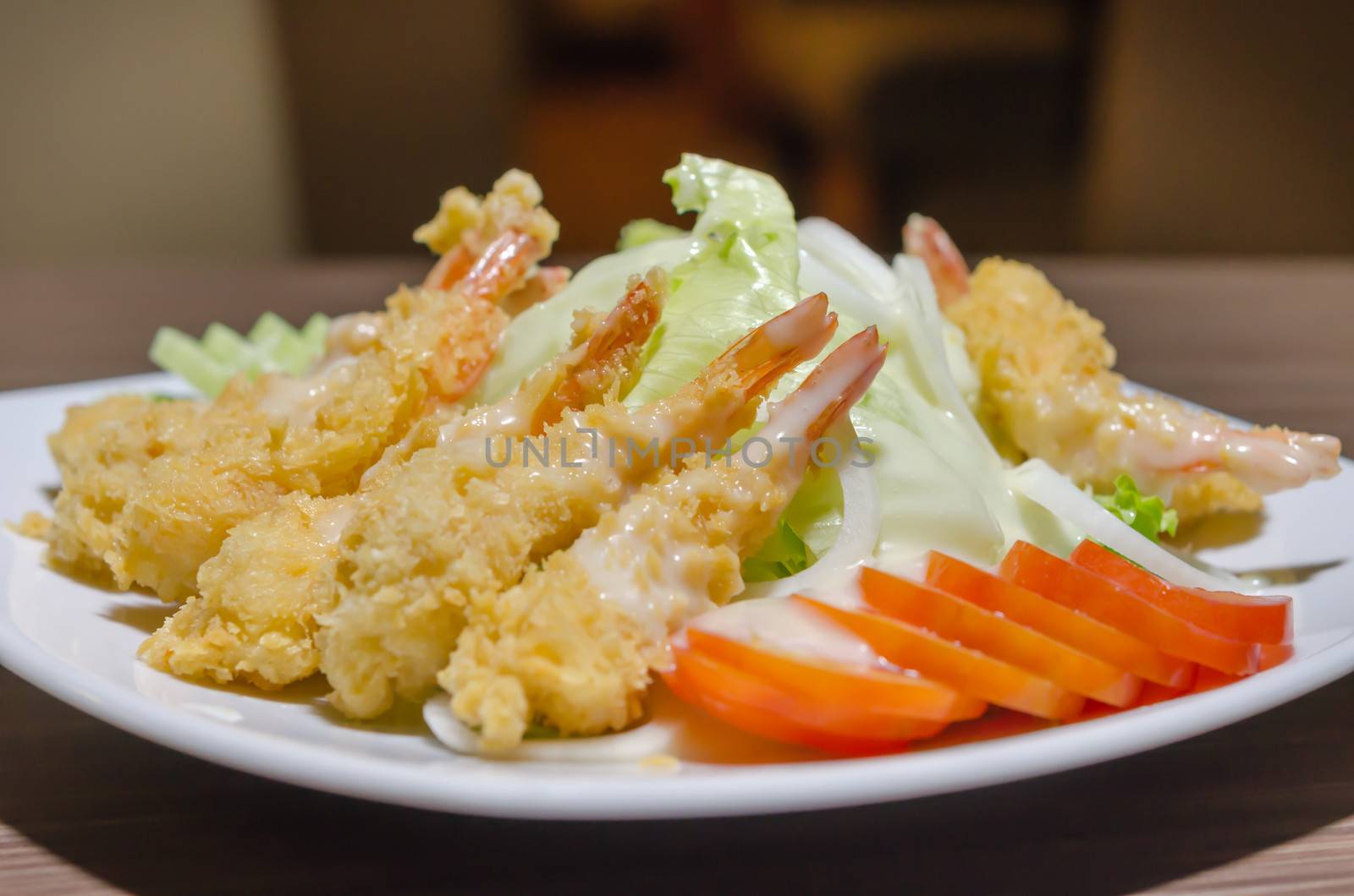 close up deep fried shrimp and  fresh vegetable salad on  white plate 