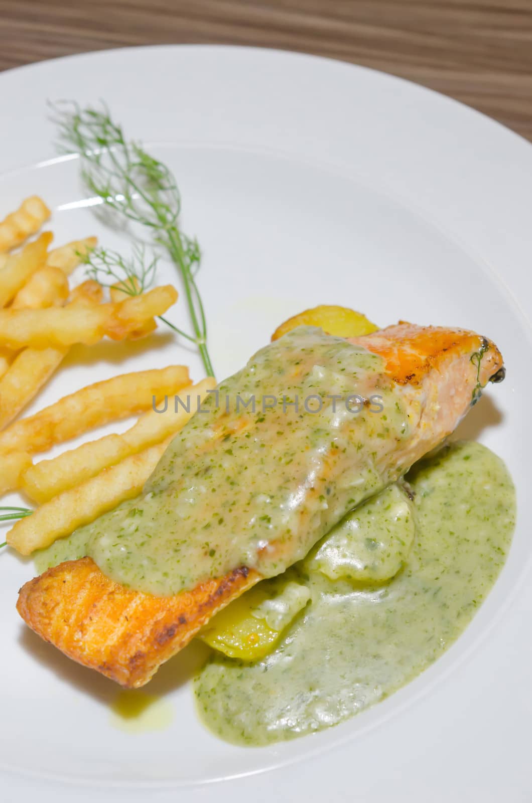 top view grilled salmon served with green sauce and french fries  on white plate