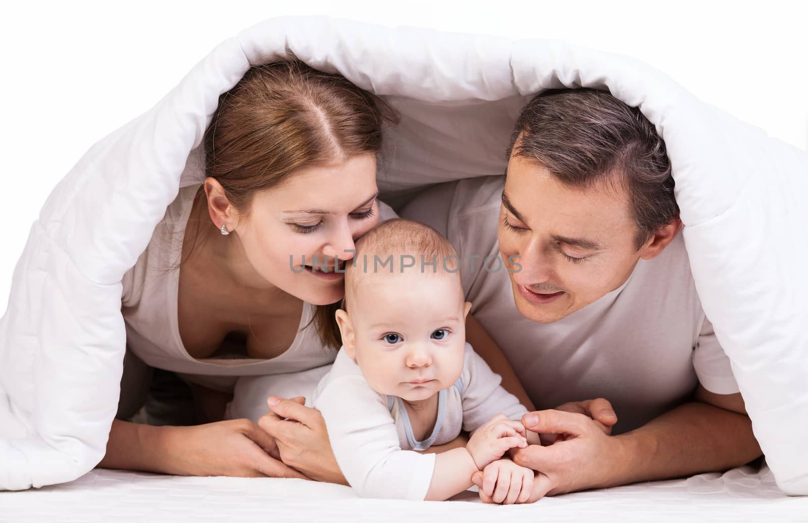 Young family with baby boy under blanket on bed over white background