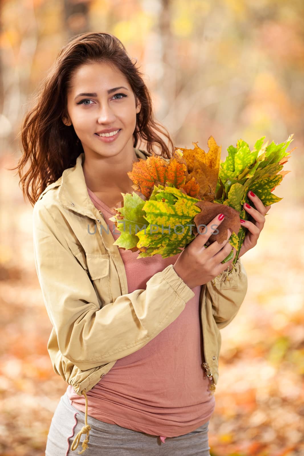 Young girl with autumn leaves in hand by photobac