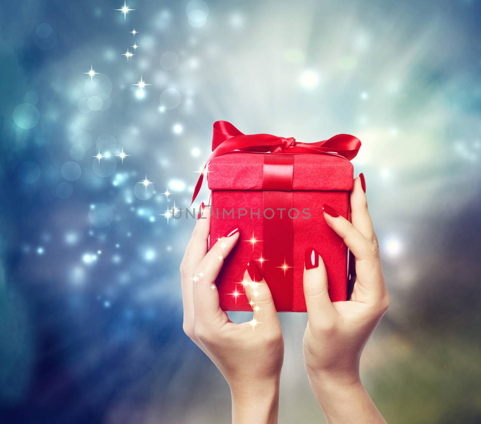 Red present box on Christmas on shinning background being held up by in a woman's hands