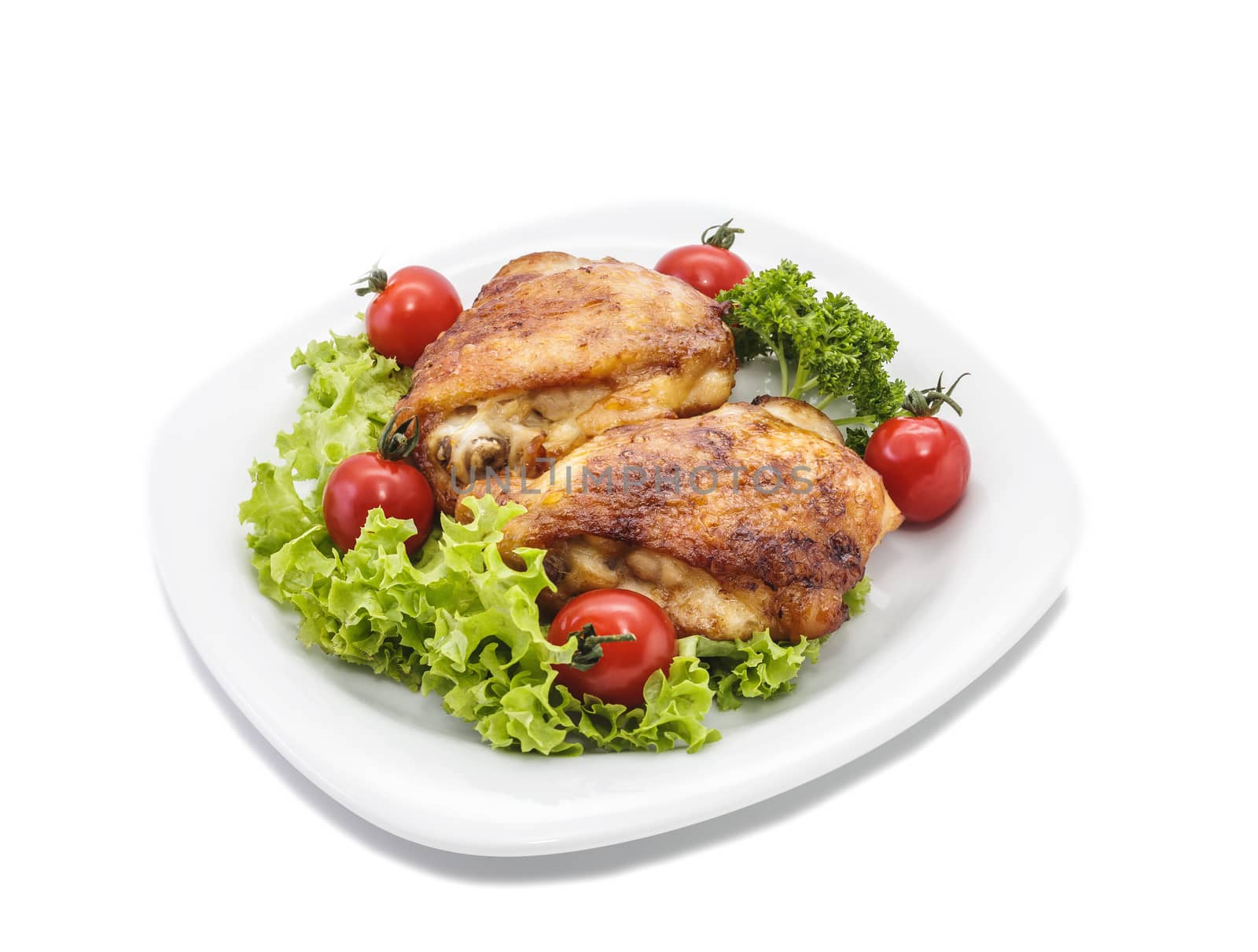 Fried chicken pieces on a plate with tomatoes, lettuce and parsley. Taken on a sheet of white plastic. Is not an isolate.