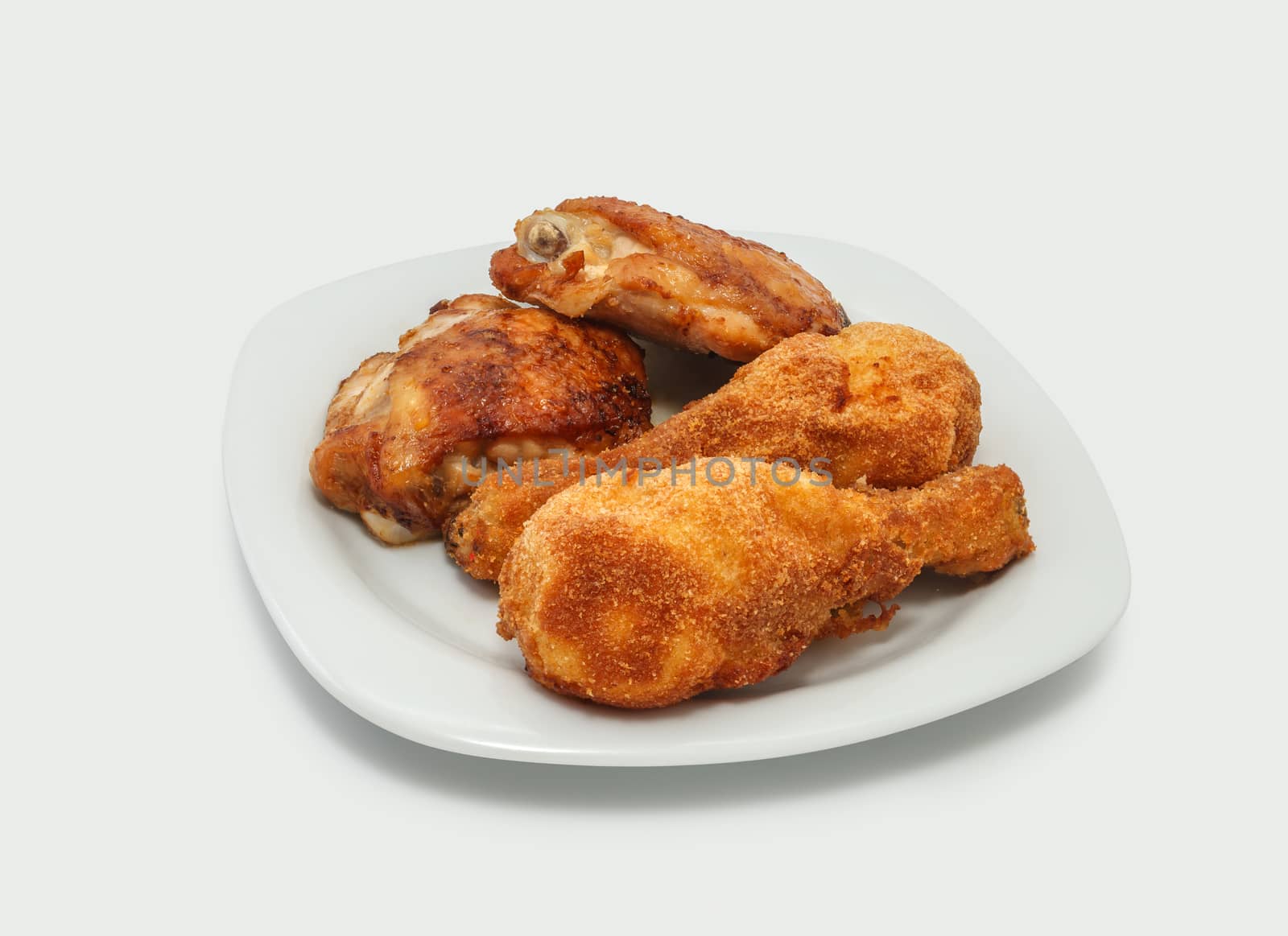Fried chicken pieces on a plate. Taken on a sheet of white plastic. Is not an isolate.