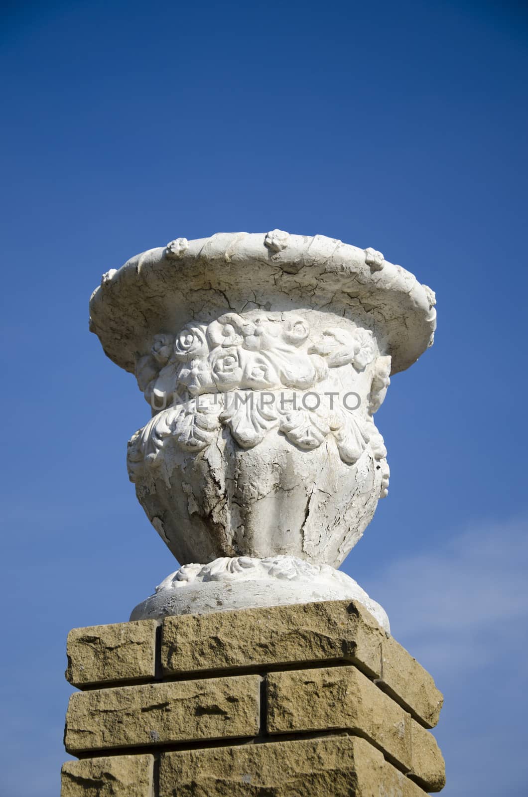 Old plaster garden vase on a modern brick pedestal on sky backgr by pt-home