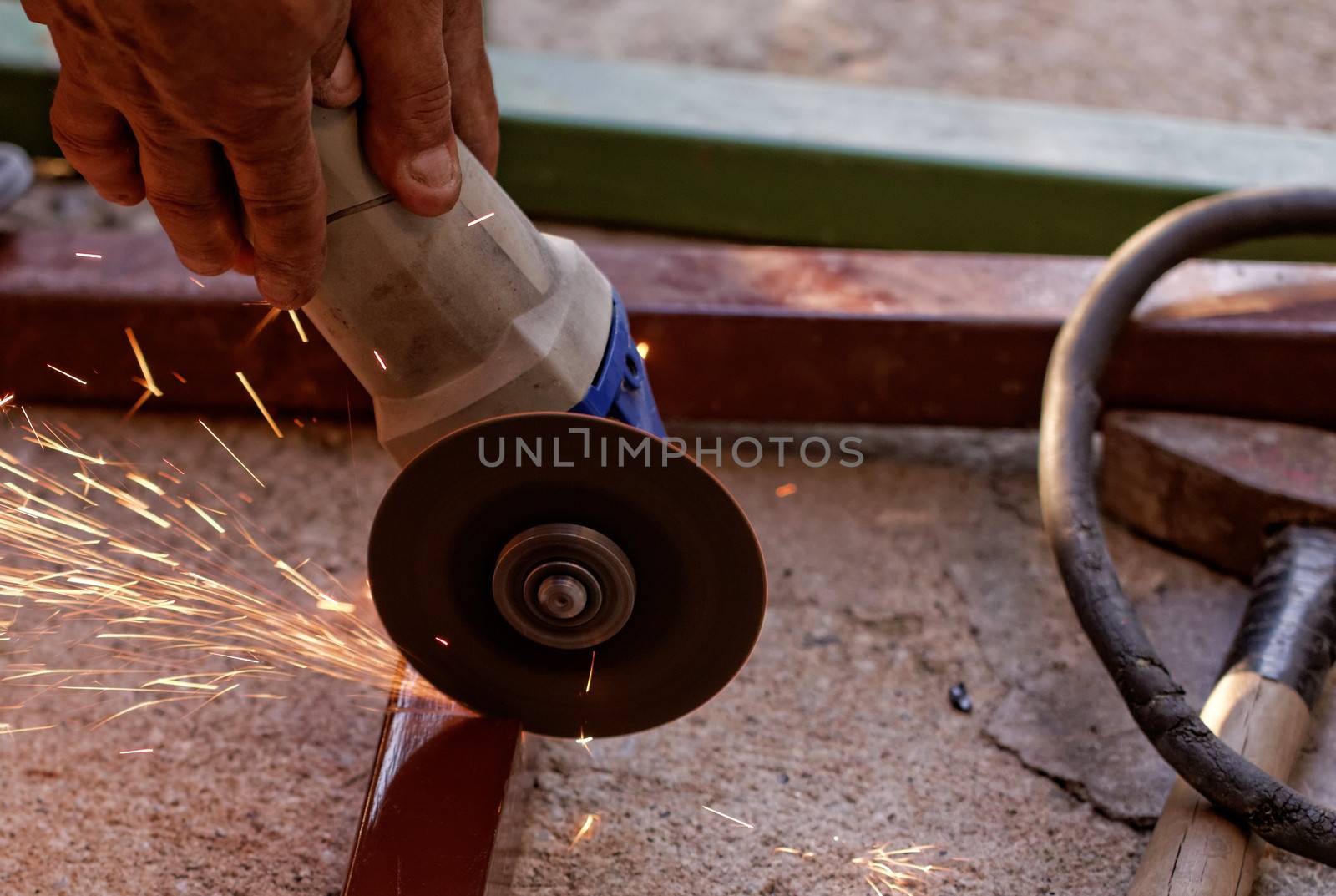 Metal sawing with hand grinder. Sparks while grinding iron.