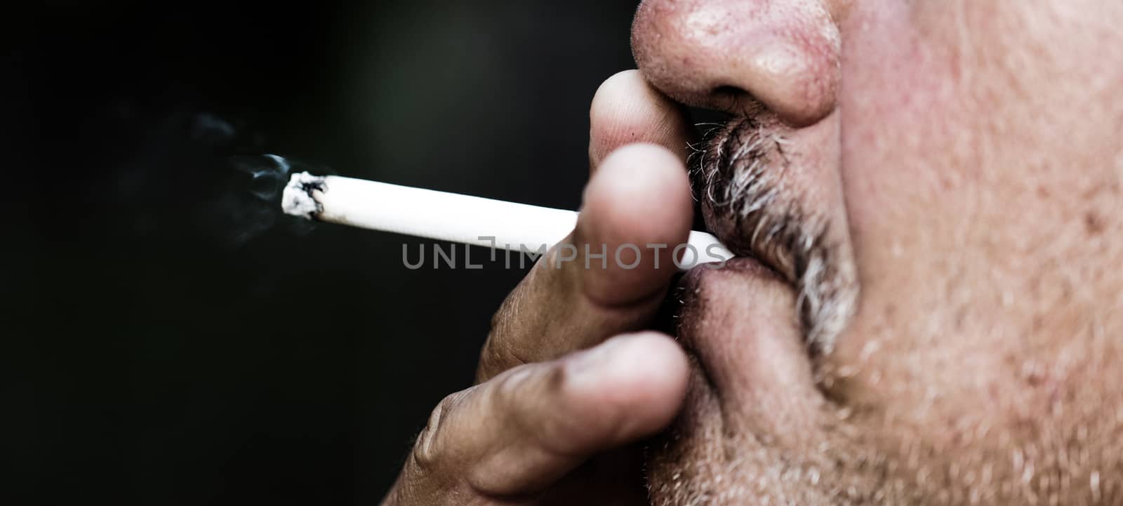 Smoking a cigarette against a dark background