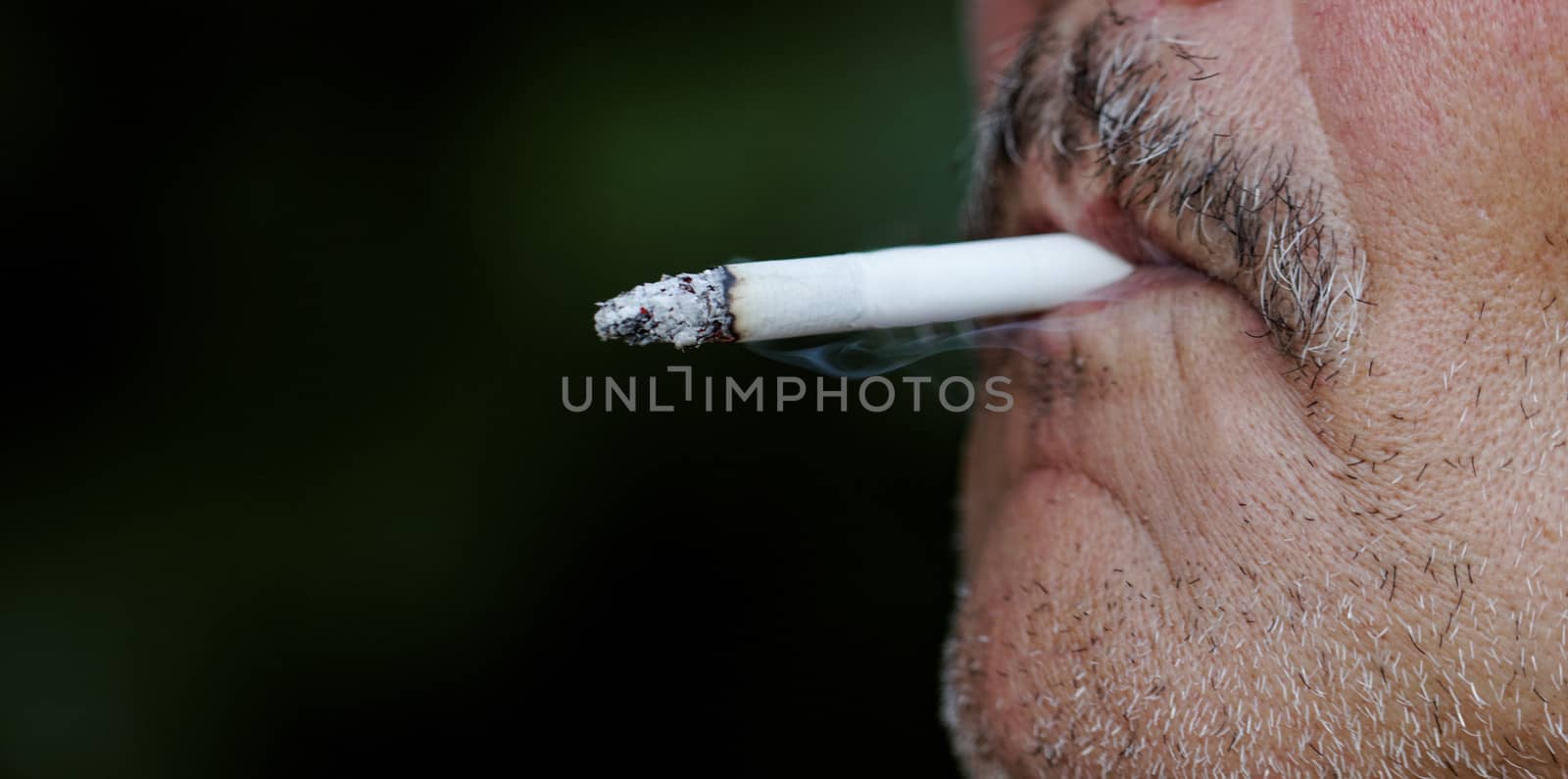 Smoking a cigarette against a dark background