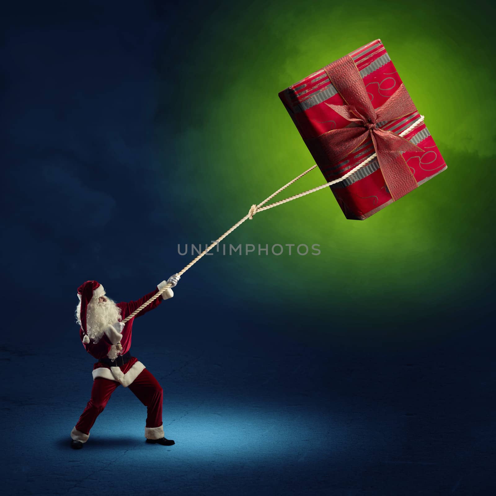 Santa Claus pulls a rope with a red box with a gift