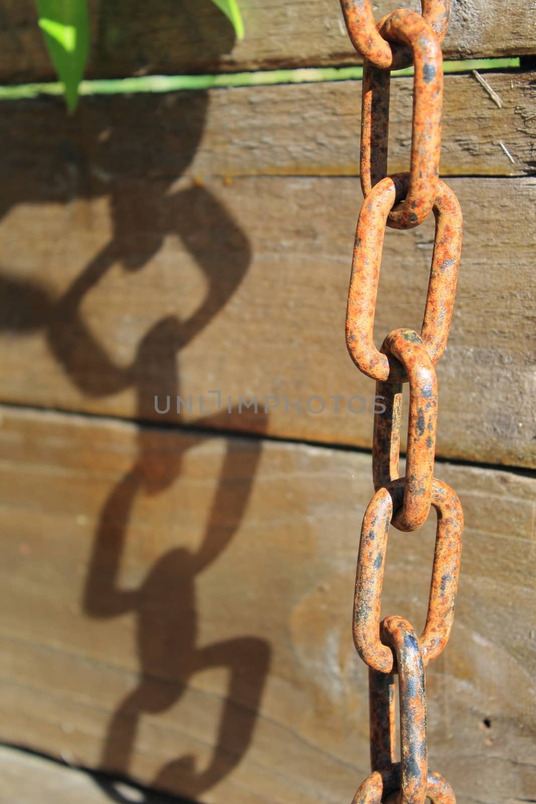 Image of a chain hanging, rusting, with shadow contrast