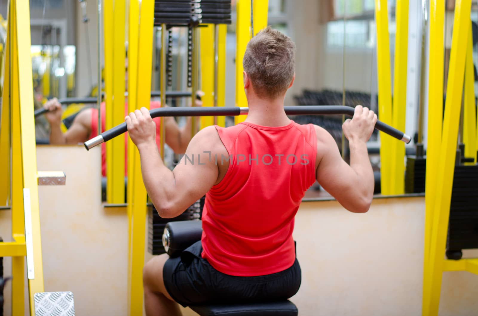 Attractive and fit young man in gym working out and exercising on equipment