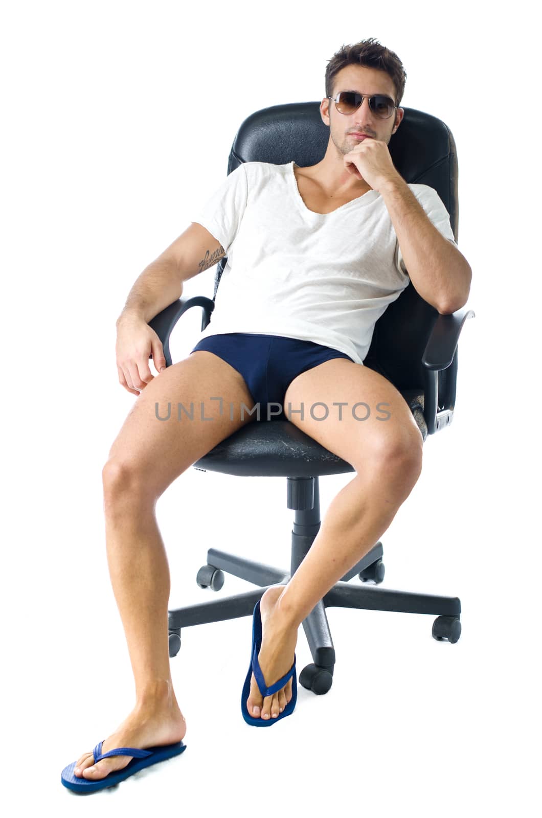 Attractive young man in t-shirt, with naked legs on office chair, isolated on white background