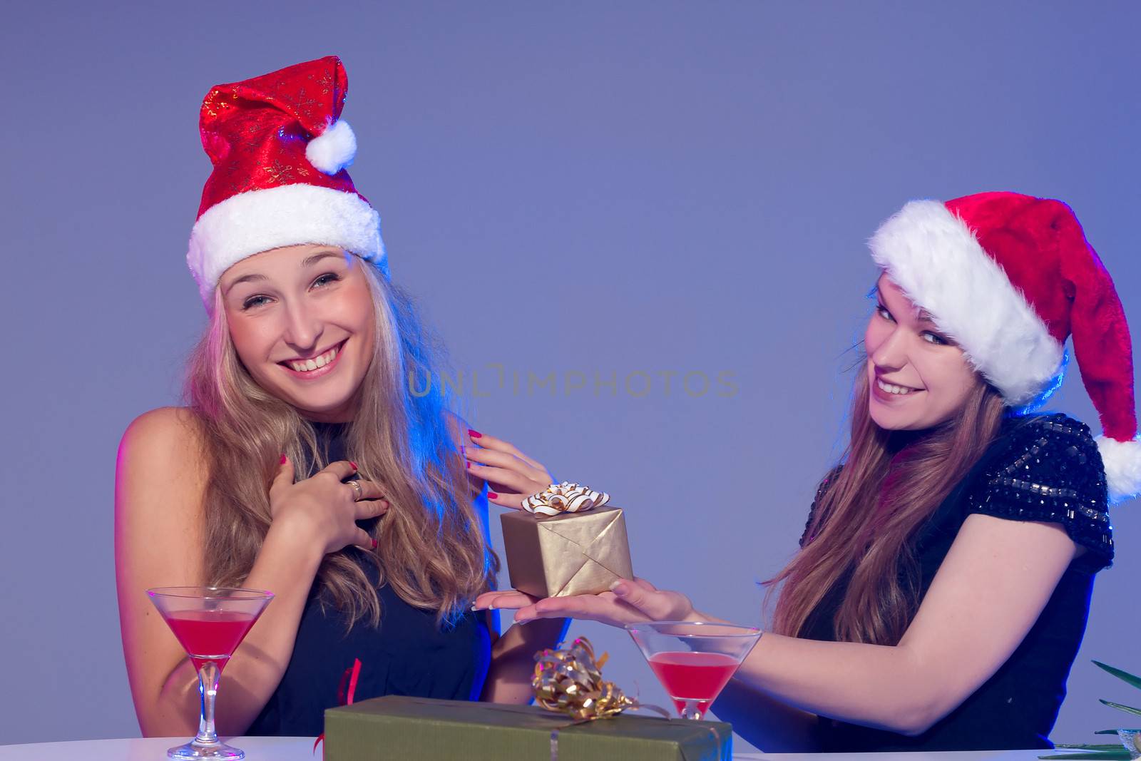 Girlfriends in Christmas hats with cocktails by victosha