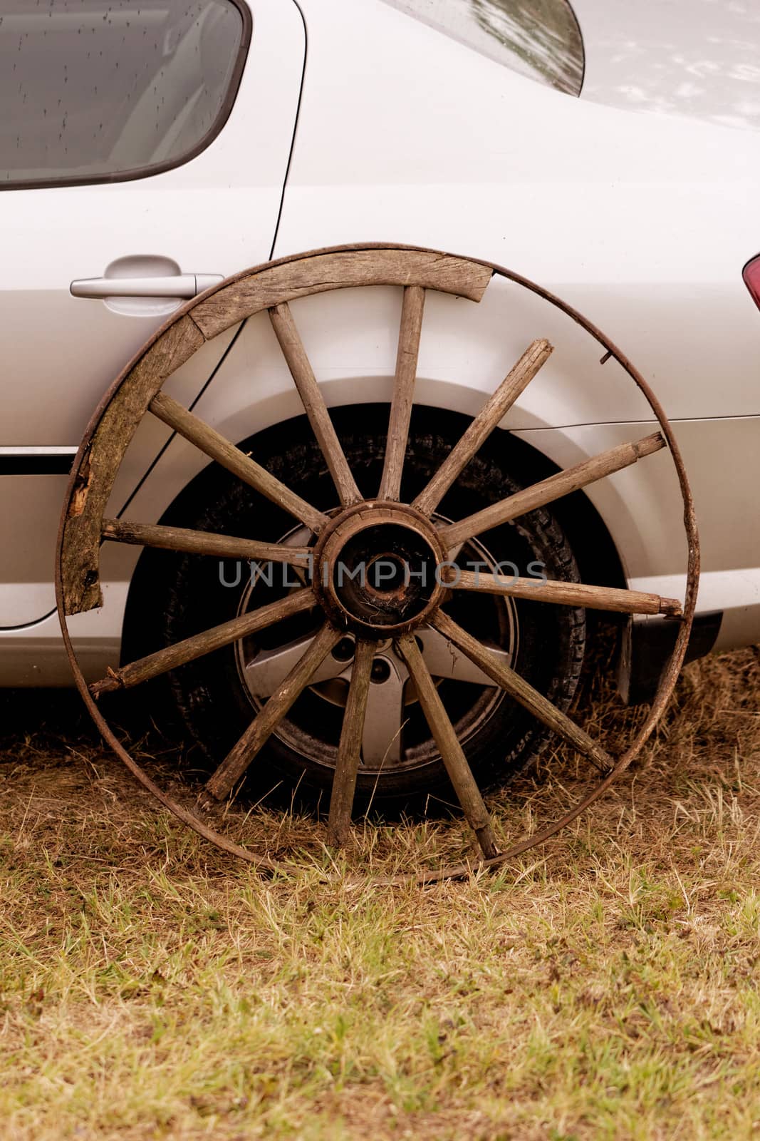 old broken wagon wheel side by new cars back