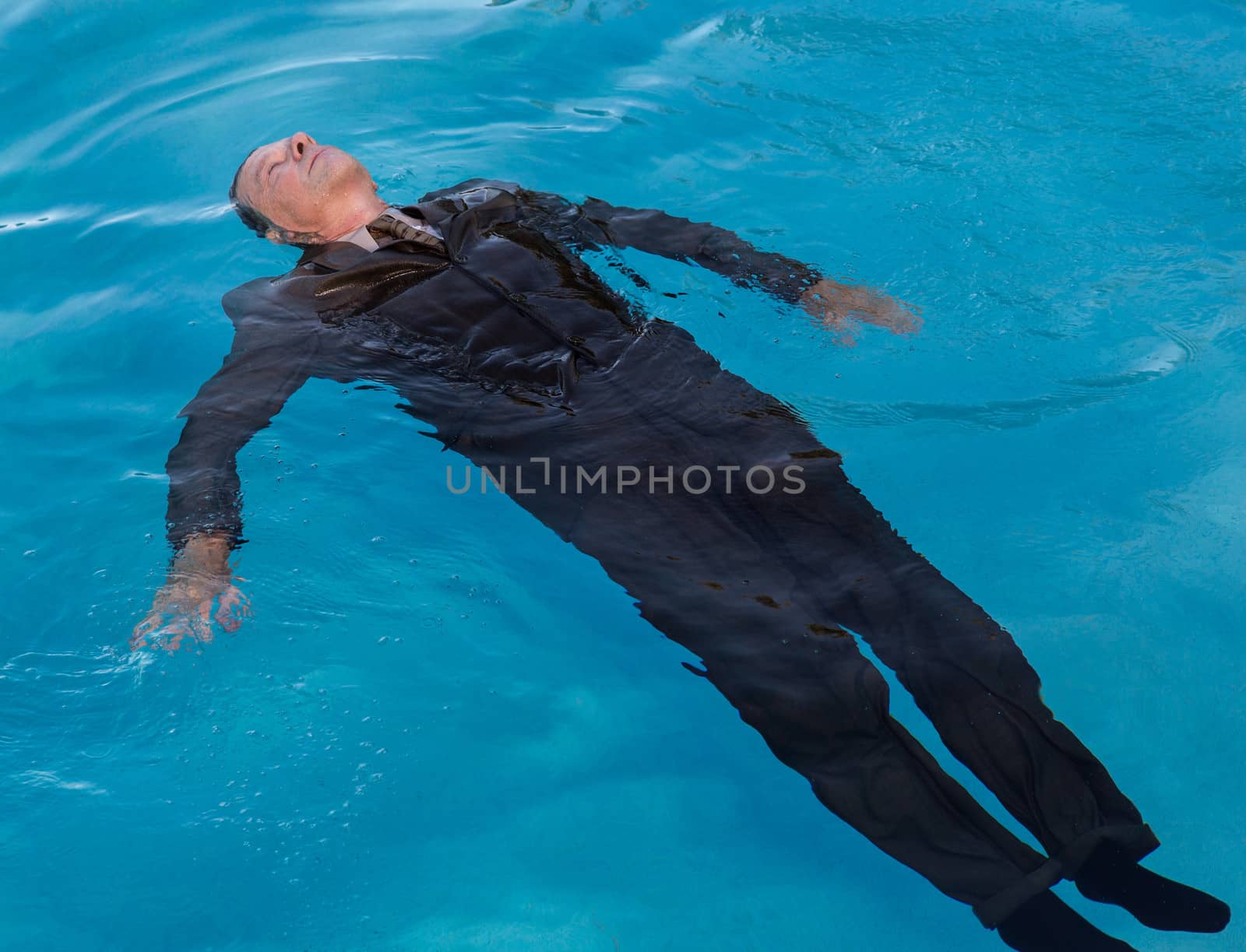 Senior caucasian businessman in suit sinking underwater in deep blue pool looking like drowning as a result of problems