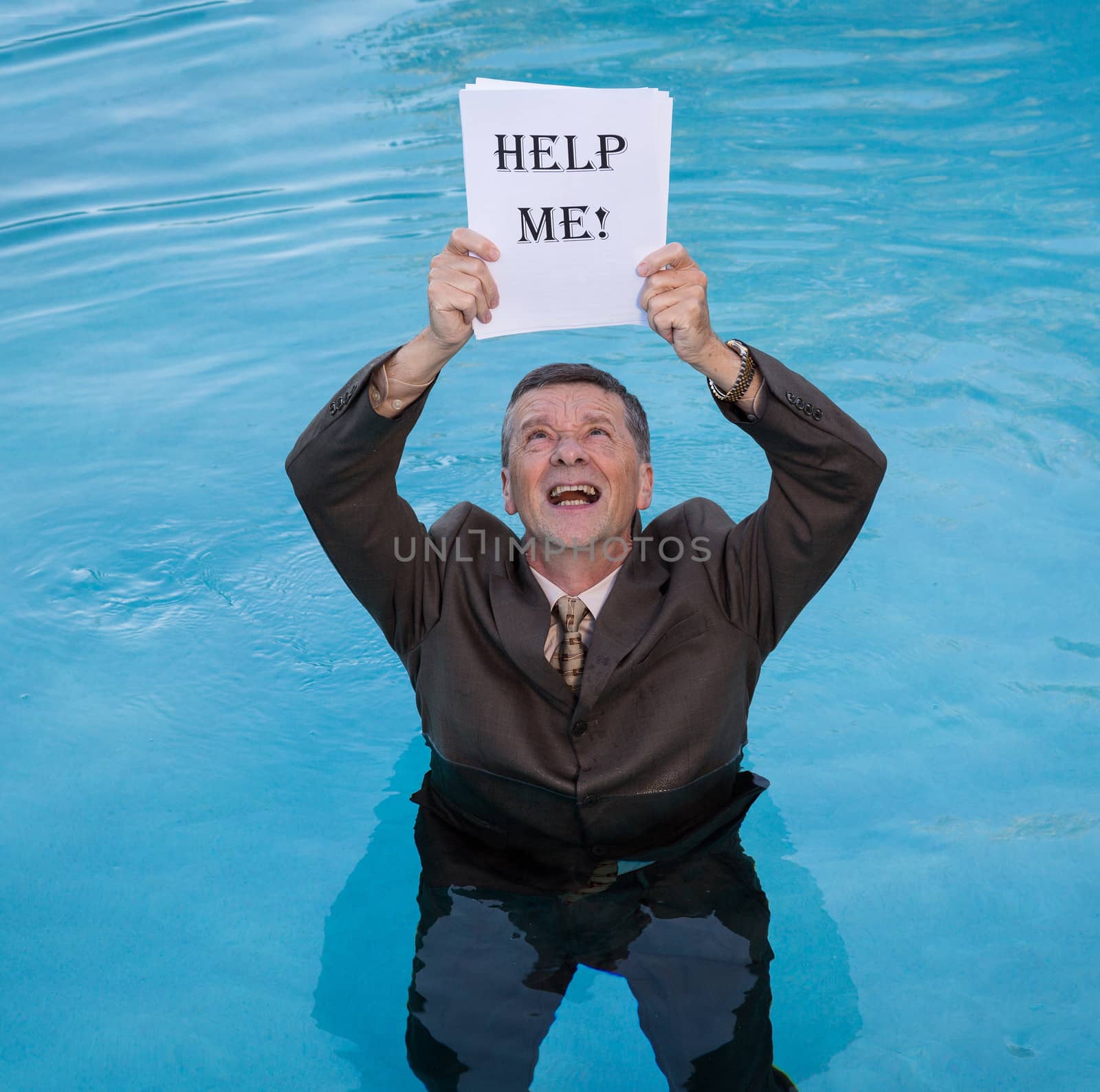 Senior caucasian businessman in suit up to waist in deep blue water worried about drowning in paperwork and holding help me document