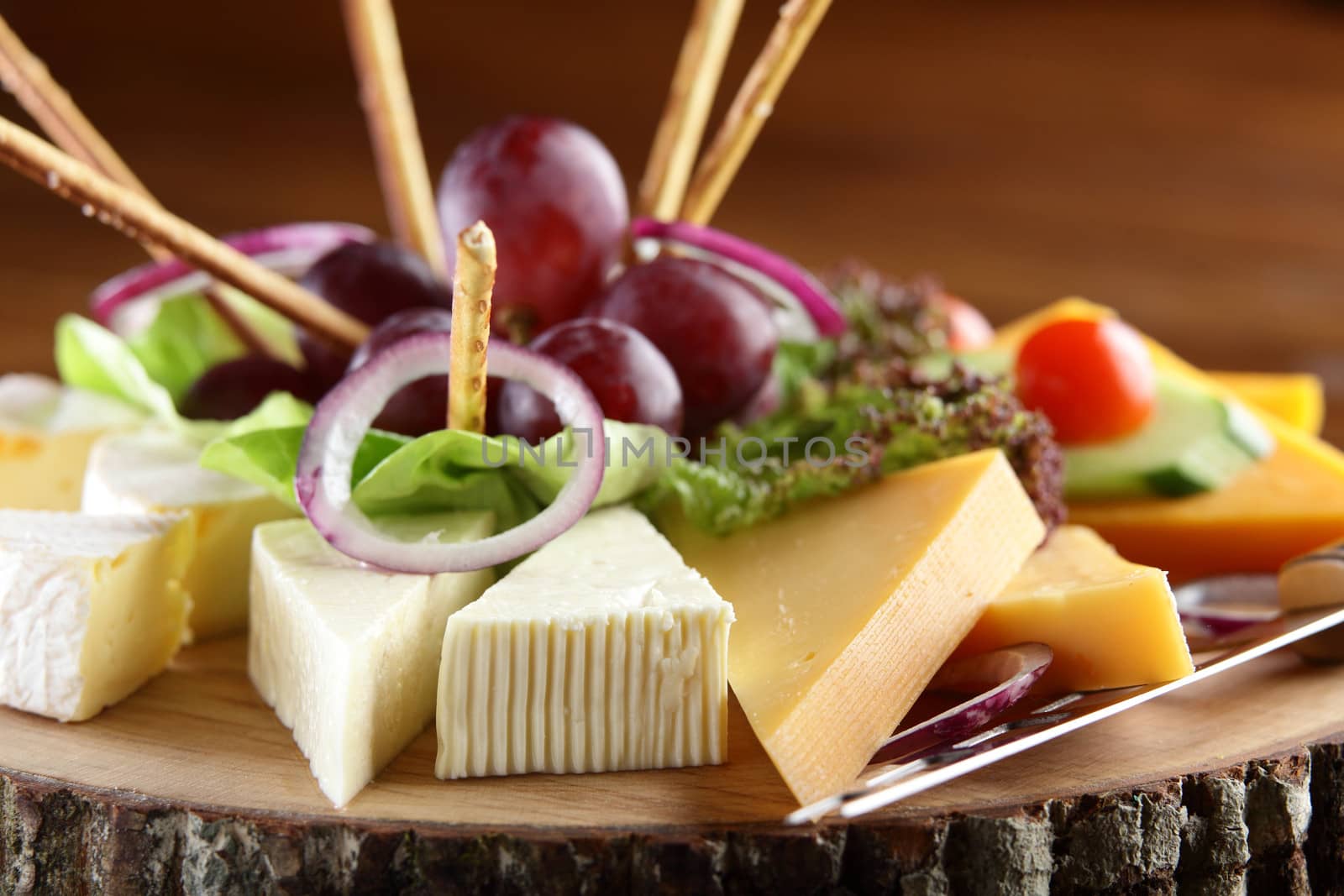 cold and tasty cheese and fruits on wooden dish
