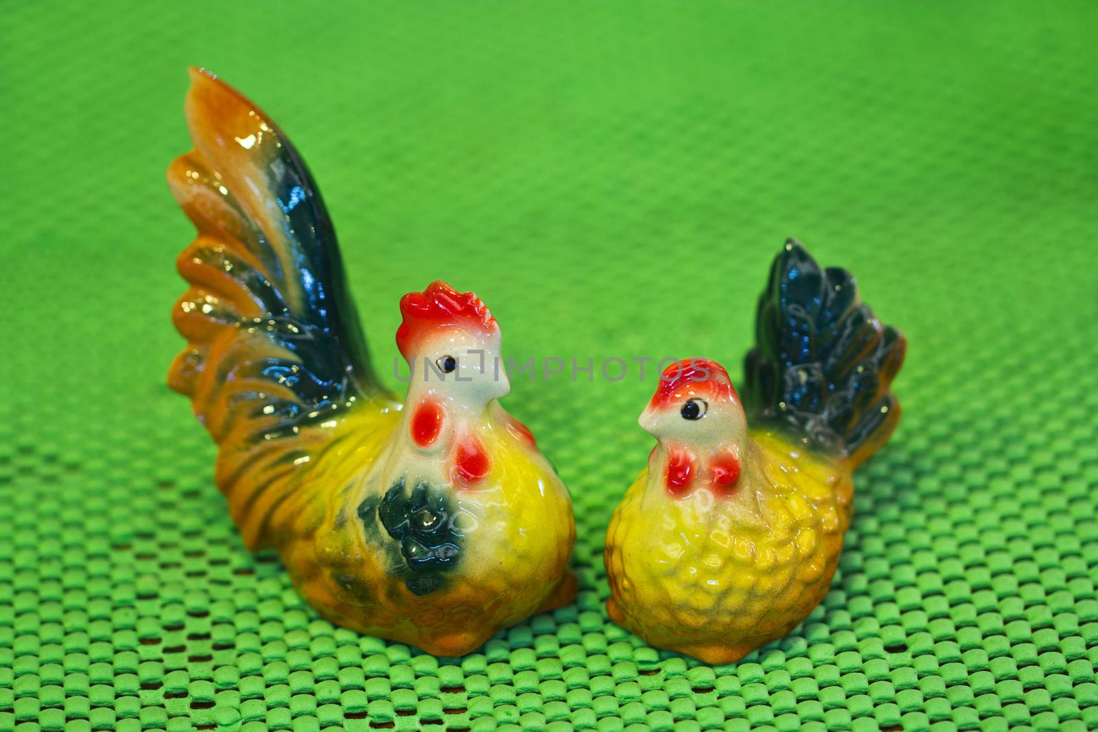 Cute ceramic chicken on green background, in Thailand.