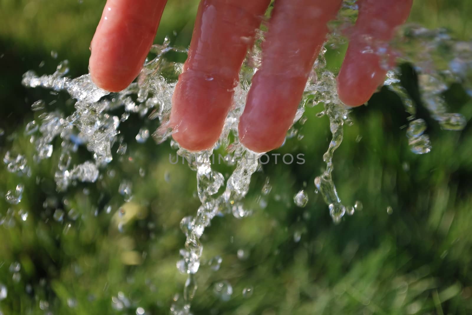 Cold water and hand on green background. 