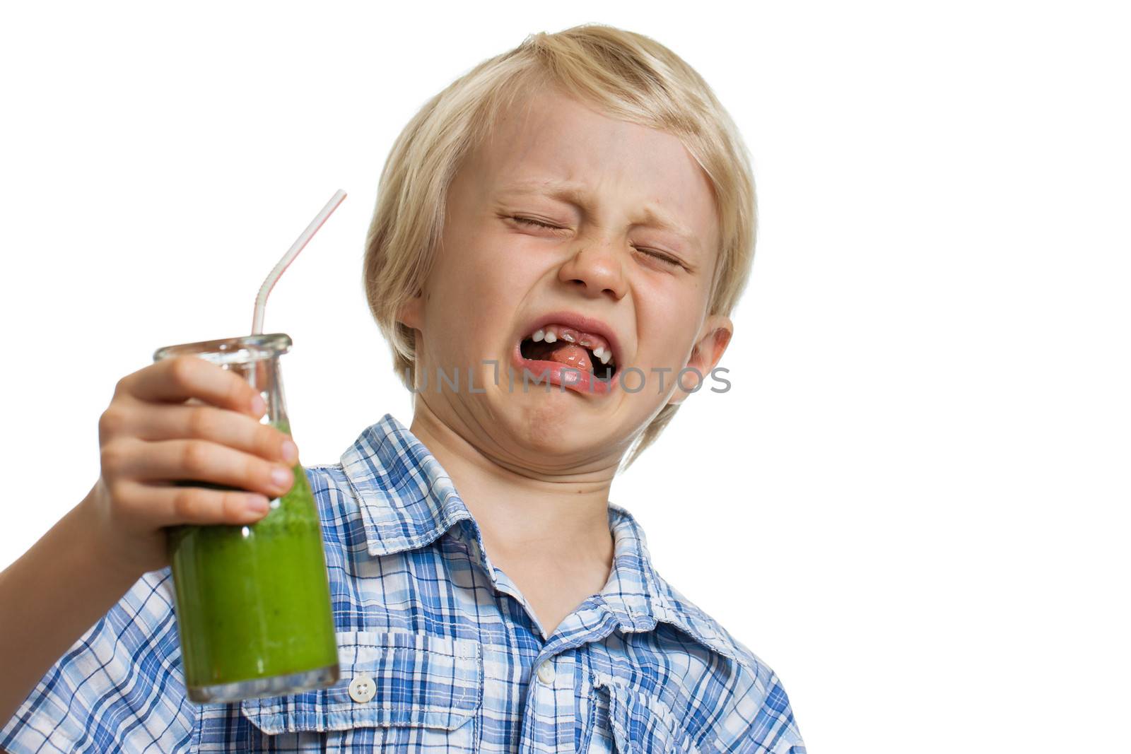 A young boy looking very disgusted holding a green smoothie. Isolated on white.