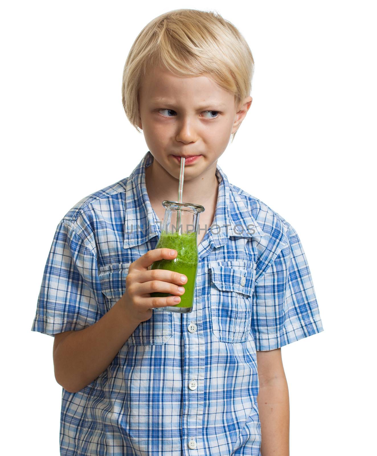 A cute boy, looking suspicious while drinking a green smoothie. Isolated on white.